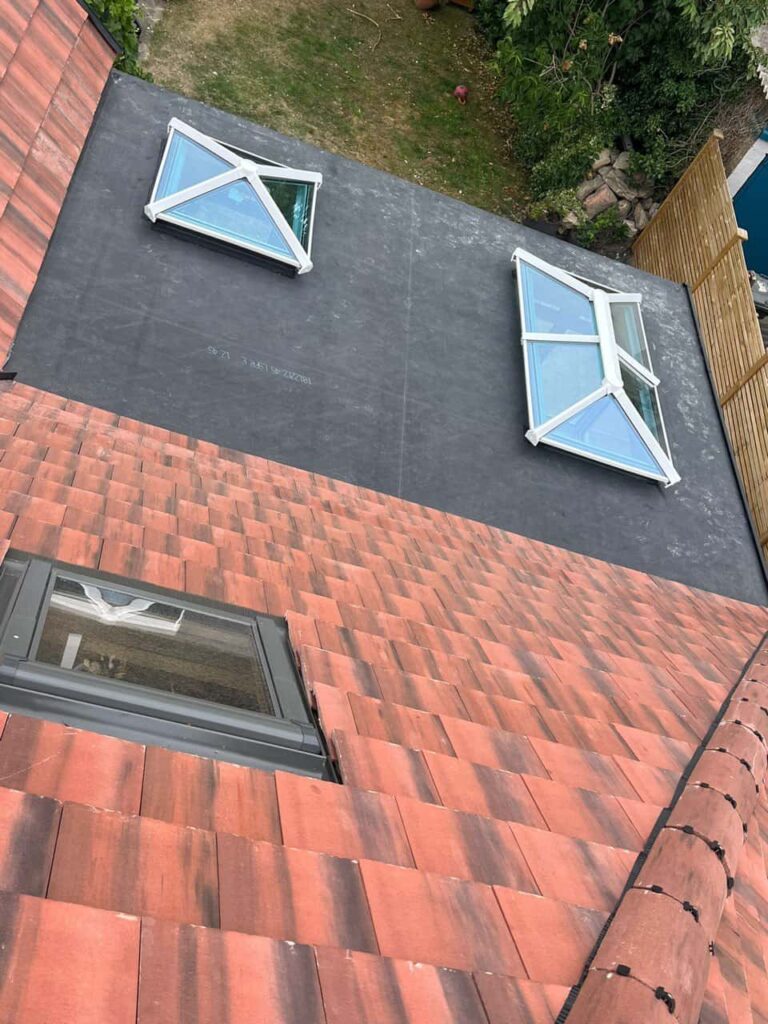 This is a photo taken from the roof ridge looking down a tiled pitched roof on to a flat roof. Works carried out by Ollerton Roofing Repairs